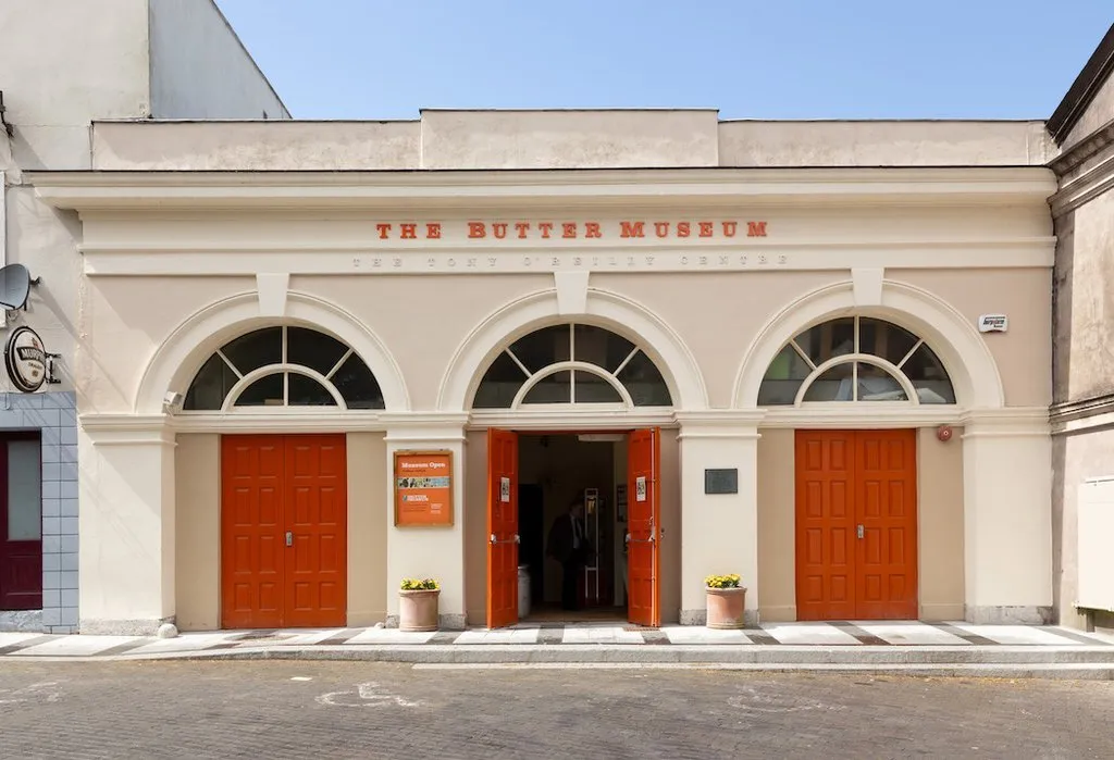 Photograph of the Butter Museum, county Cork. A cream building with three red doors.