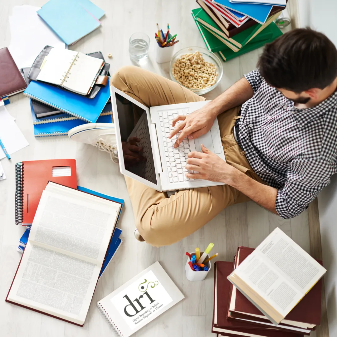 Person typing on laptop surrounded by notebooks