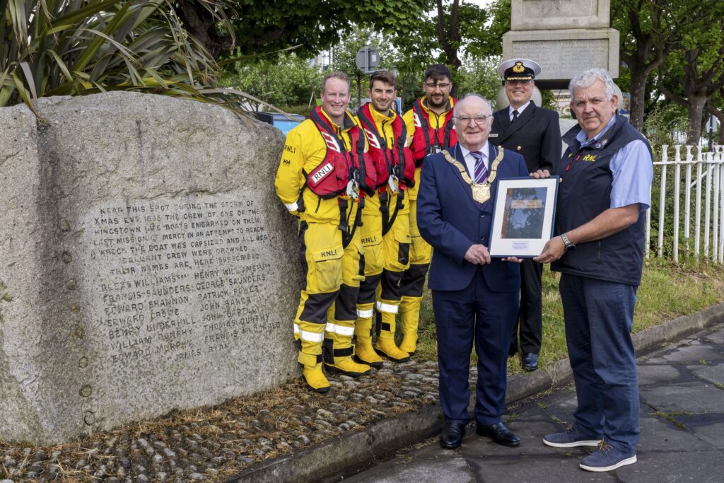 Image of lifeboat sailors being presented with a framed copy of the cover of the Kingstown Lifeboat Disaster Fund Letter Book.