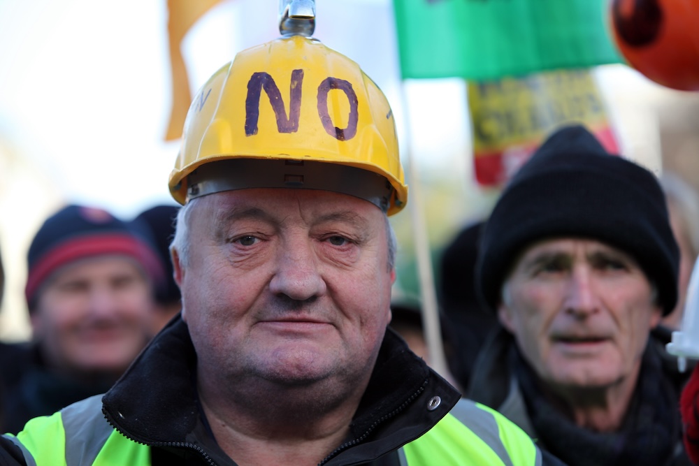 Man wearing yellow hardhat with NO written in black ink.